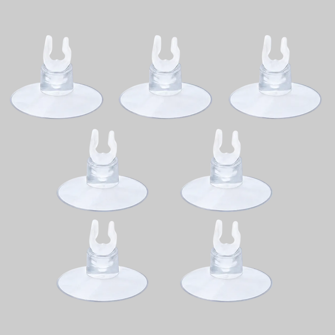 Seven clear aquarium suction cup clips arranged on a light blue background, commonly used for holding airline tubing, heaters, or aquarium accessories in fish tanks.
