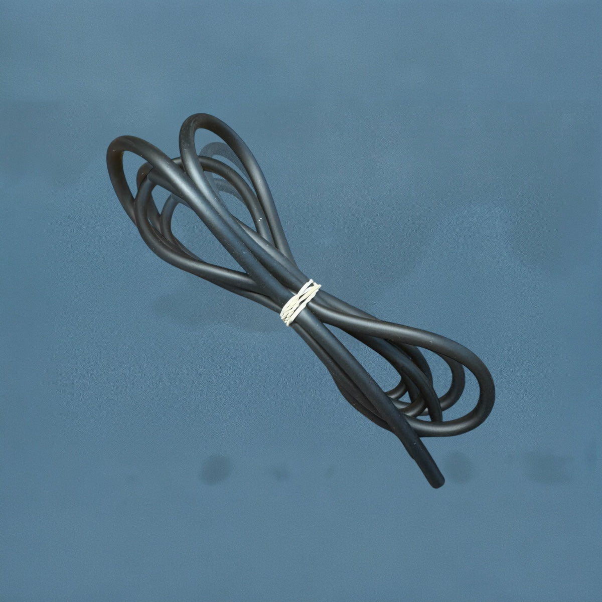 Coiled black aquarium airline tubing displayed against an ocean blue background. The flexible tubing is looped neatly and secured in the center with a white twist tie, showing its smooth matte texture. Ideal for connecting air pumps, air stones, and aquarium accessories.