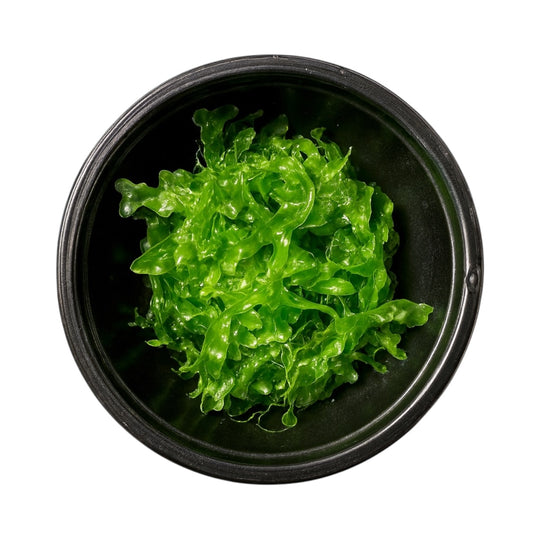 Top-down view of bright green Subwassertang moss in a black bowl on a white background.