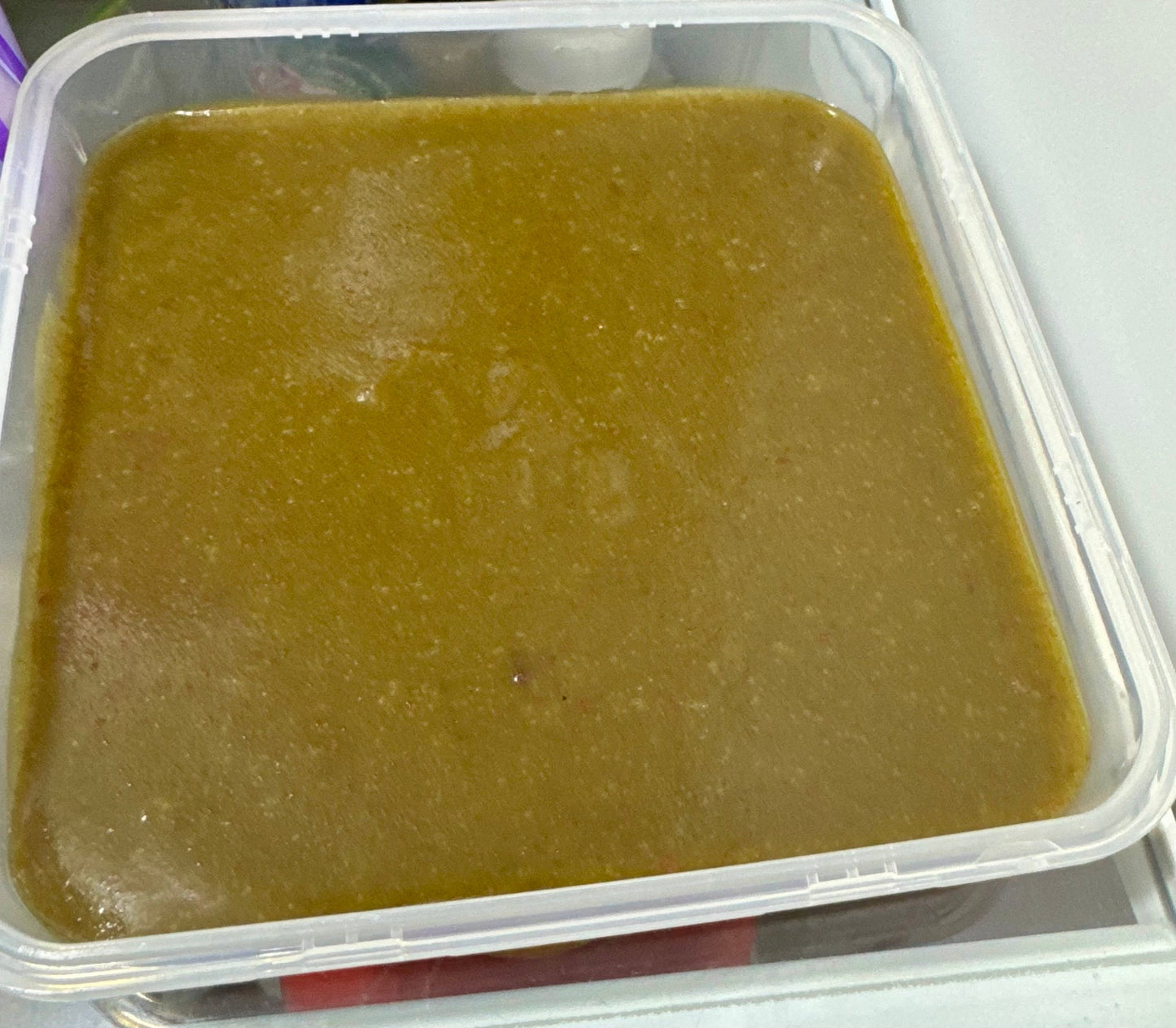 Close-up view of a pan filled with freshly prepared Snail-O snail food, showing its smooth, greenish-brown texture and even surface, used as a nutritious calcium-rich diet for aquarium snails.