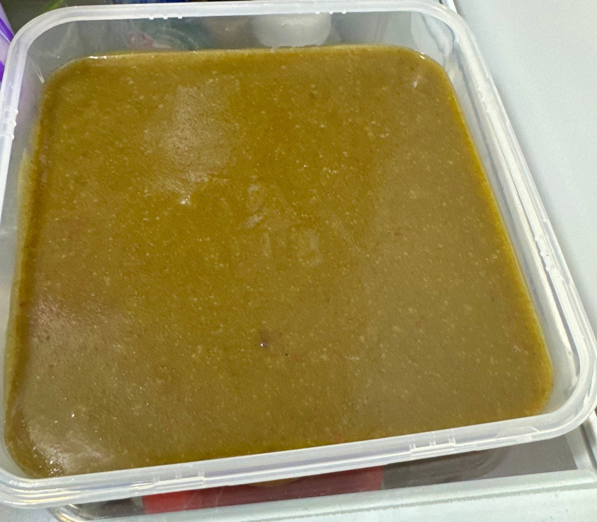 Close-up view of a pan filled with freshly prepared Snail-O snail food, showing its smooth, greenish-brown texture and even surface, used as a nutritious calcium-rich diet for aquarium snails.