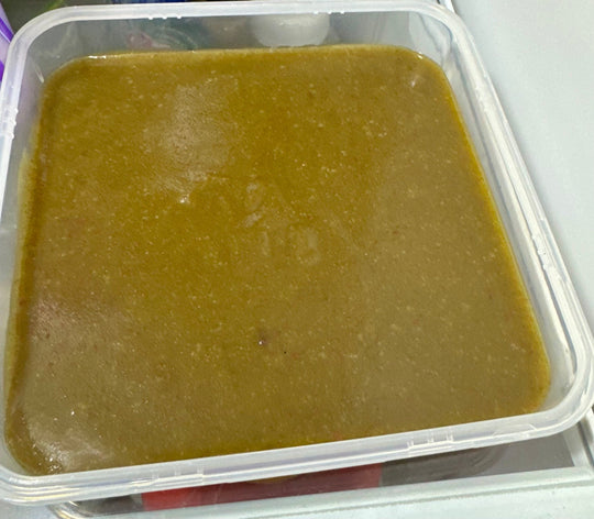 Close-up view of a pan filled with freshly prepared Snail-O snail food, showing its smooth, greenish-brown texture and even surface, used as a nutritious calcium-rich diet for aquarium snails.
