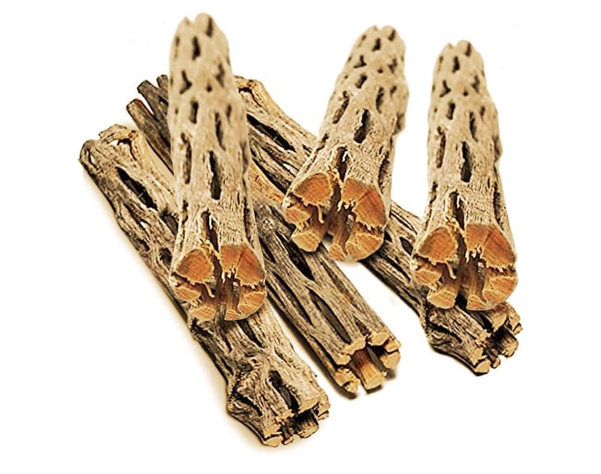 May include: A group of six brown cholla  wood. The sticks are arranged in a pile with the ends of the sticks facing the viewer. The sticks are dry and have a rough, textured surface. The sticks are a natural brown color with some areas of lighter brown and orange.