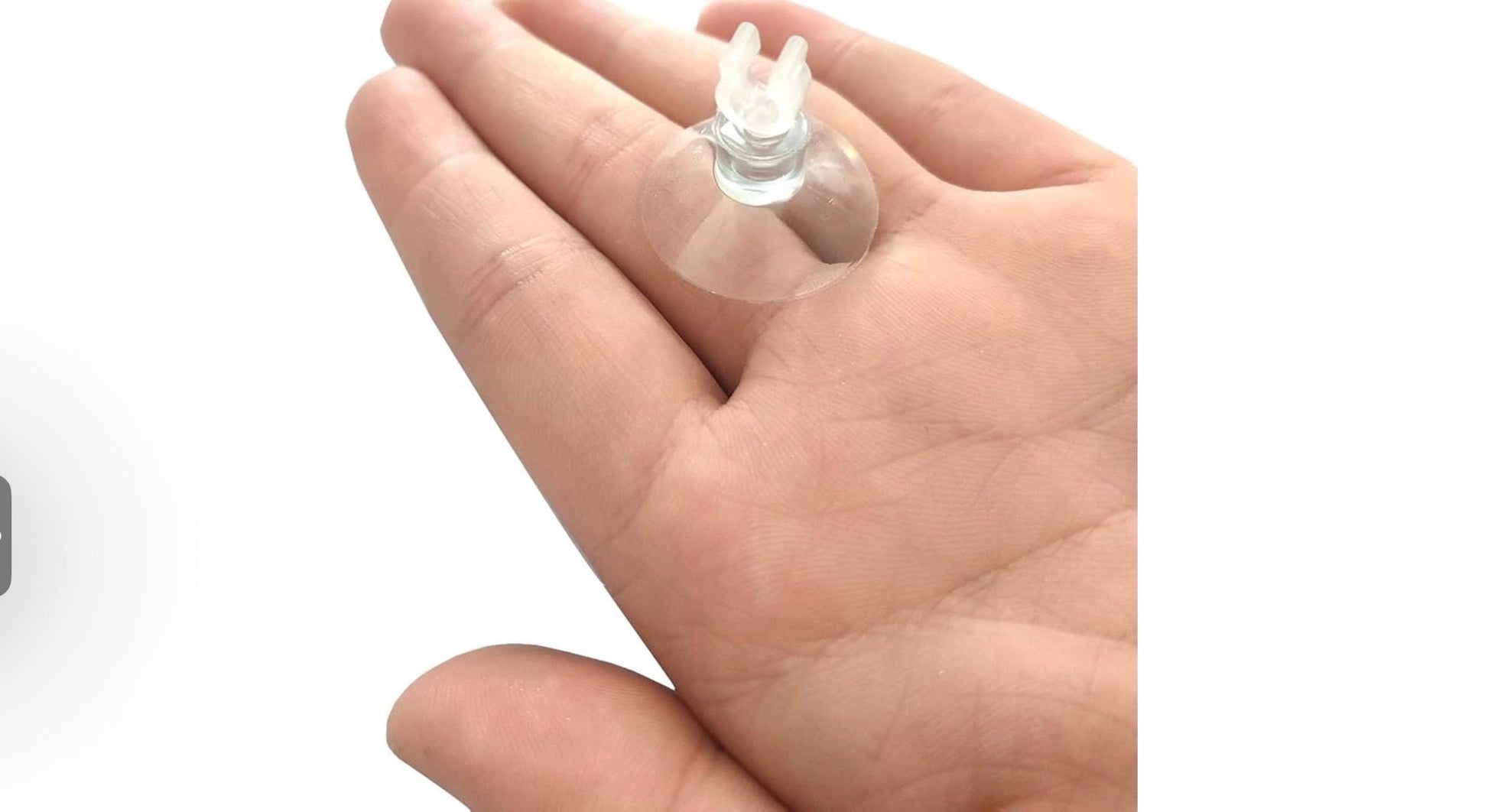 Clear aquarium suction cup with clip holder shown resting on a hand for scale, used to secure airline tubing inside fish tanks and attach air hoses to glass surfaces.