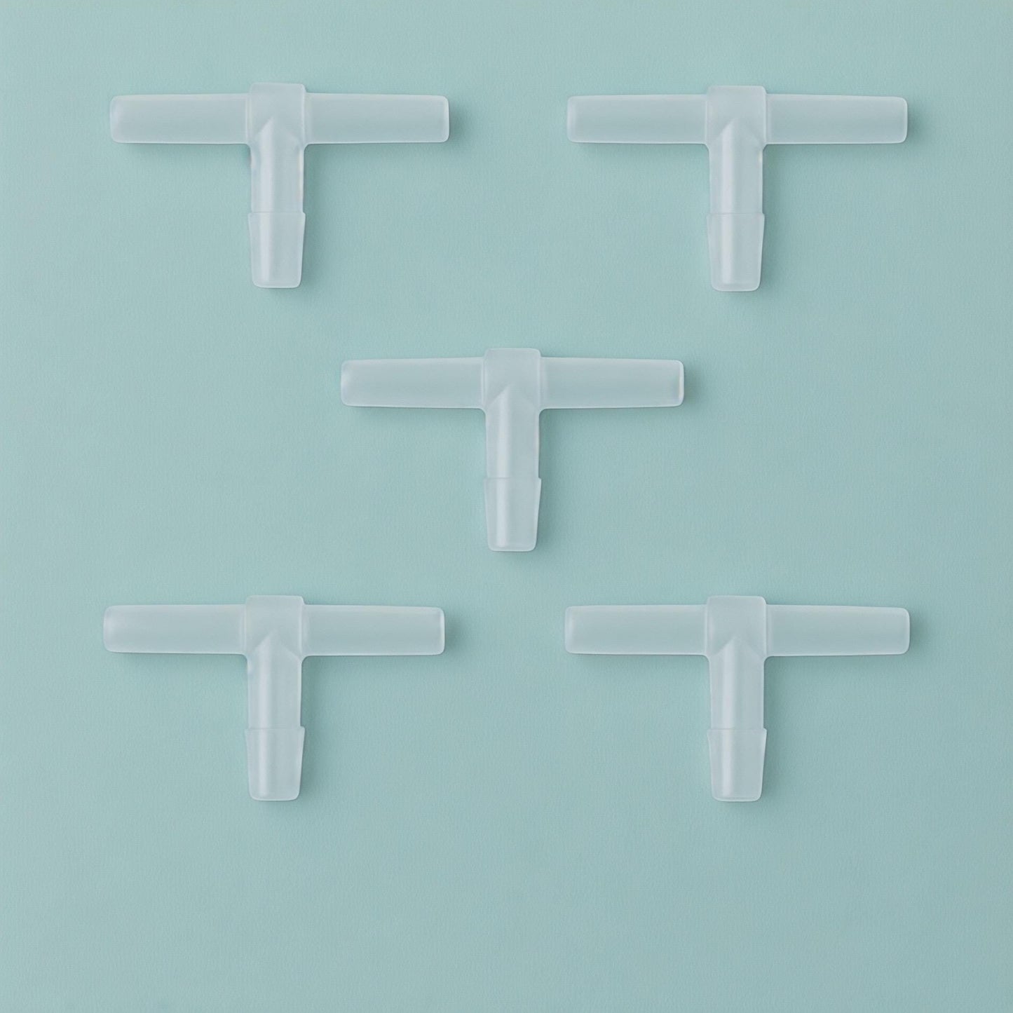 Five transparent T-shaped aquarium airline tubing connectors arranged in a dice-style pattern on an Aqua Mist background (#B7D8D2), shown in a clean, minimalist square composition with soft lighting for an Etsy product photo.